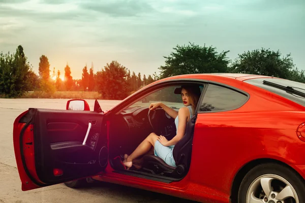 Κυρία με κόκκινα χείλη που κάθεται στο κόκκινο αυτοκίνητο άθλημα — Φωτογραφία Αρχείου