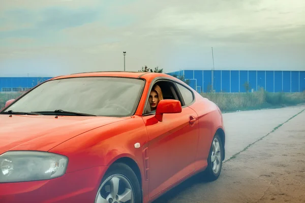 Frau mit roten Lippen am Steuer eines roten Autos — Stockfoto