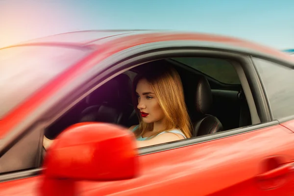 Mladá žena s červenými rty řídit auto — Stock fotografie