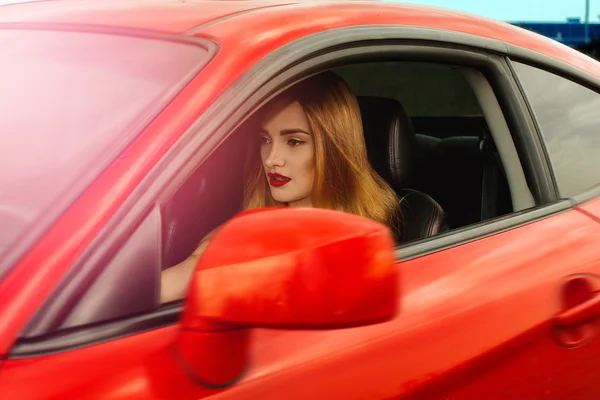 Mädchen mit roten Lippen am Steuer eines Autos — Stockfoto