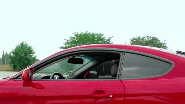 Mujer se sienta en el coche deportivo rojo — Vídeo de stock