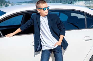 çocuk beyaz bir arabanın yakınında poz güneş gözlüğü