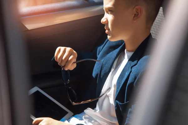 Riche garçon assis sur un siège arrière de la voiture — Photo