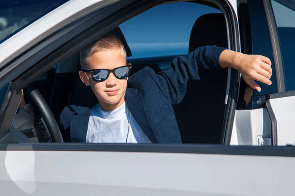 Niño en gafas de sol se sienta en el coche —  Fotos de Stock