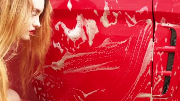 Молодая девушка моет красную машину — стоковое видео