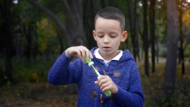 Mavi kazaklı genç dışarıda sabun köpüğü üflüyor.