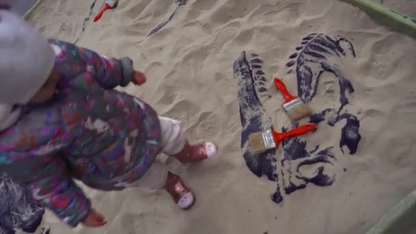 Little Cute Toddlergirl Lancia Spazzole Rosse Sandbox Con Scheletro Dinosauro — Video Stock