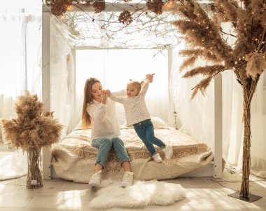 Anne evde, yatak odasında kızıyla oynuyor.