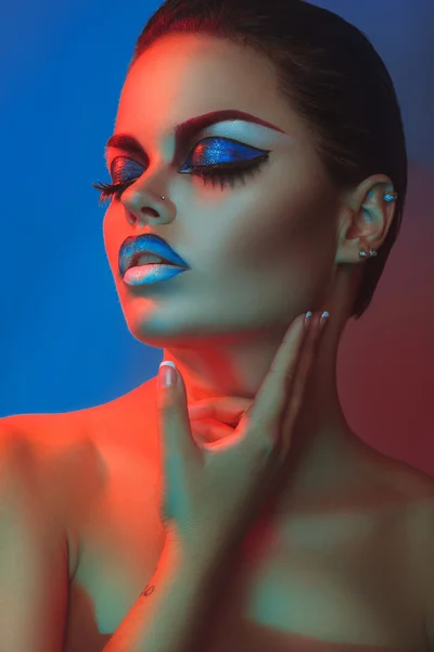 Sexy woman with make up and closed eyes in red and blue lights — Stock Photo, Image