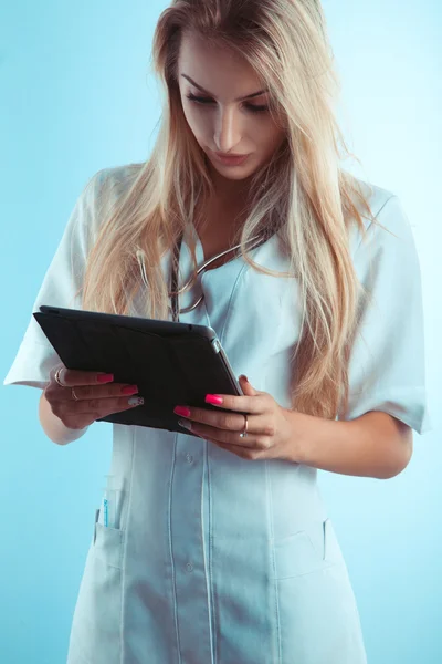 Color photo of beautiful blonde nurse reading on tablet — Stock Photo, Image