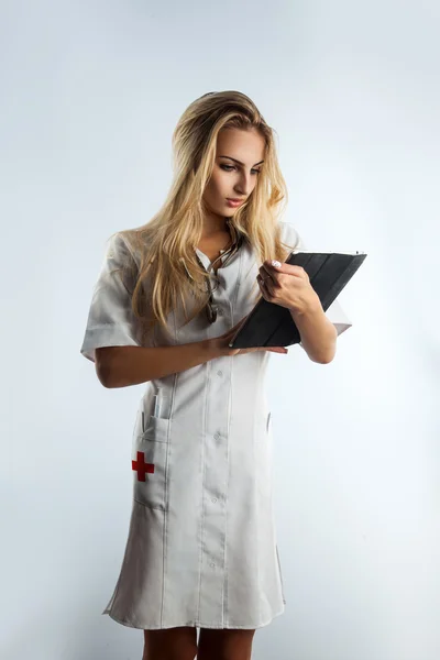 Vertikales Foto der jungen sexy Krankenschwester mit Stethoskop und Tablette — Stockfoto