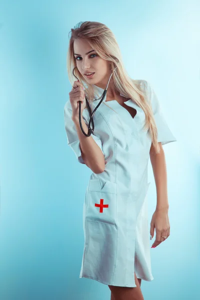 Dulce enfermera rubia con estetoscopio en bata médica blanca —  Fotos de Stock