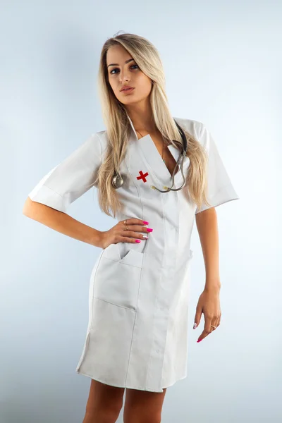 Adult blonde beautiful nurse in white medical gown — Stock Photo, Image