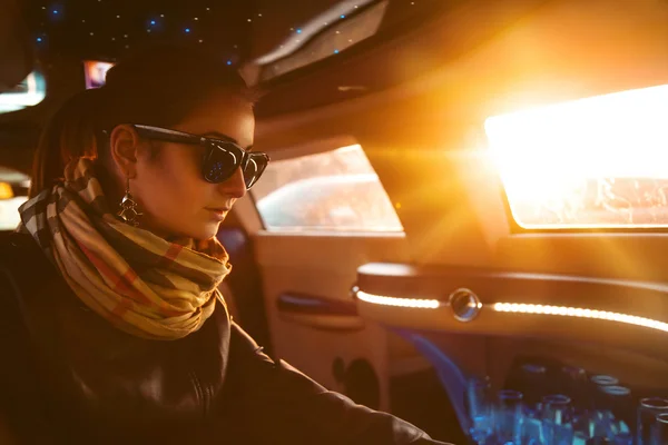 Modell i skinnjacka och solglasögon sitter i limousine — Stockfoto