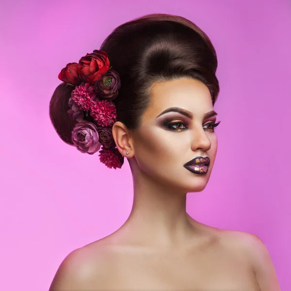 Mooie volwassen brunette met make-up kapsel en bloemen in h — Stockfoto