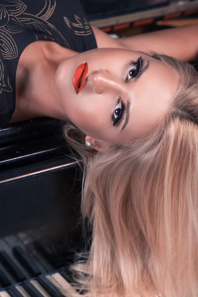 El retrato a la moda de la mujer rubia al piano mirando la cámara — Foto de Stock