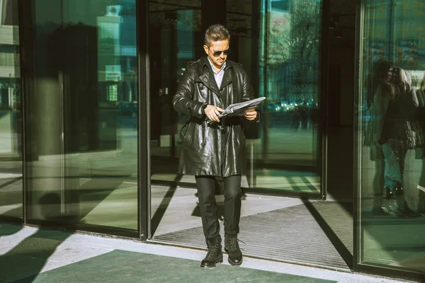 Volwassen glamour man loopt uit deuren met krant in handen — Stockfoto