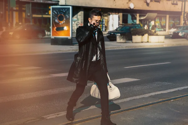 一件皮外套和太阳镜横过马路的人 — 图库照片