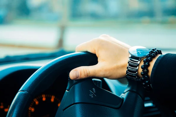 Male hand with bracelet and watch driving a car — Stock Photo, Image
