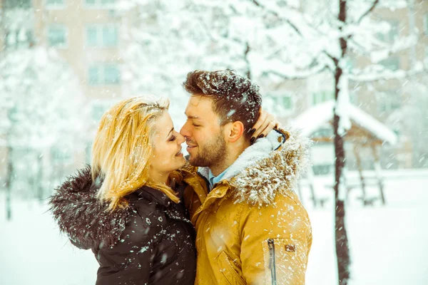 Paar umarmt und schaut sich im Schnee in die Augen — Stockfoto