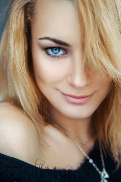 Fashionable young blonde girl with blue eyes looking at camera a — Stock Photo, Image