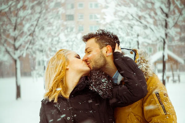 Homme et femme s'embrassant joyeusement dans la rue dans la neige — Photo