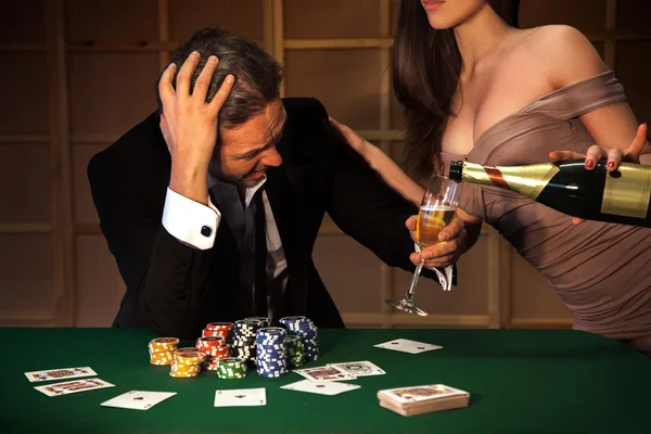 Photo emotional man loser in poker and ladies pours him a glass — Stock Photo, Image