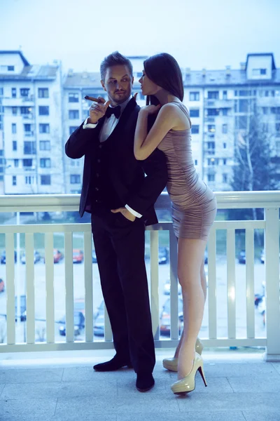 Stylish sexy man in suit with sigar looking at lady in short dre — Stock Photo, Image