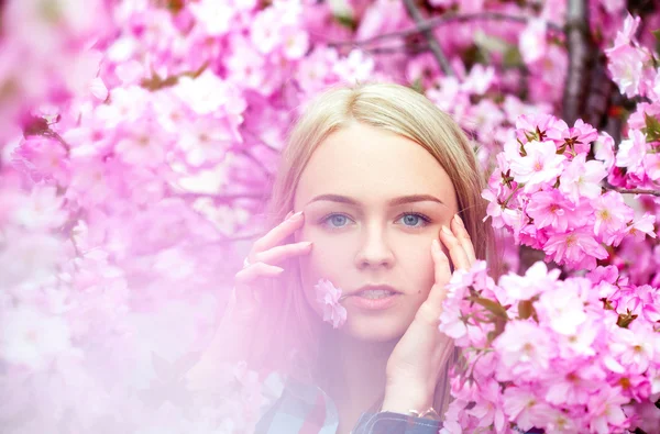 口の中でピンクの花を持つクールな若いブロンド — ストック写真