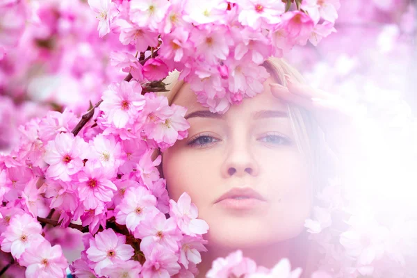 Atemberaubende junge Blondine in leuchtend rosa Blüten — Stockfoto
