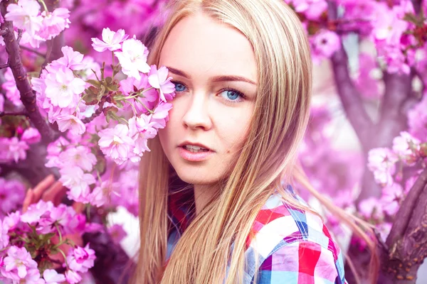 Jonge fashion model in roze bloeiende bloemen — Stockfoto