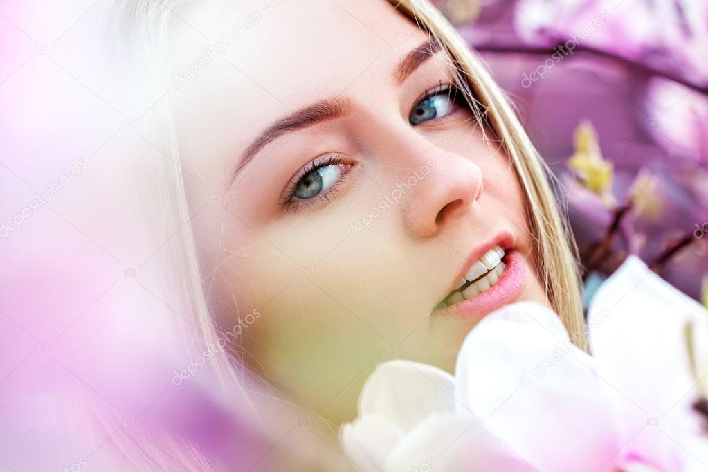 Portrait of happy young woman in blooming flowers