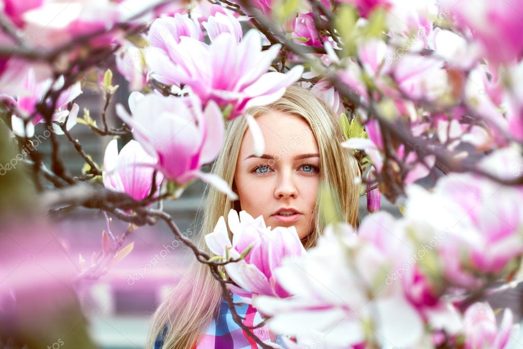 High society blond lady in pink blooming flowers looking at came