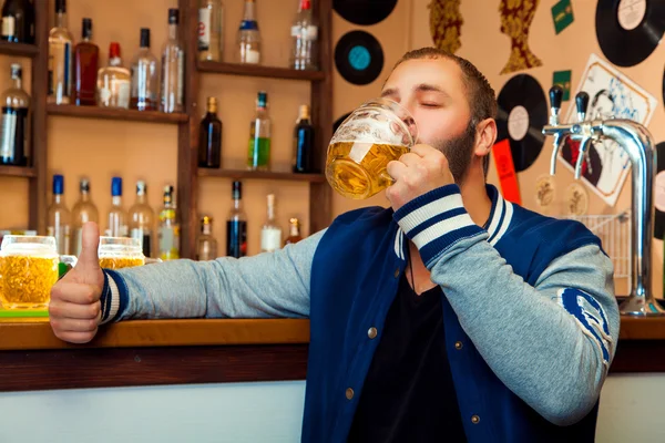 Volwassen kerel in een bar een heerlijk glas van light bier drinken — Stockfoto