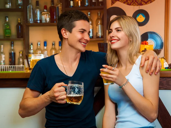 Красавица-блондинка и брюнетка мужчина улыбается и пьет в баре — стоковое фото