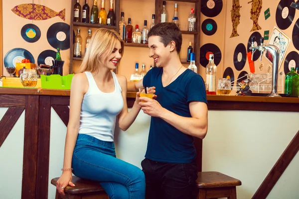 Хлопець фліртує з блондинкою в барі і дає їй коктейль — стокове фото