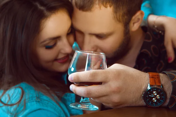 Man's hand holding a glass of cognac and in the background coupl — Stock Photo, Image