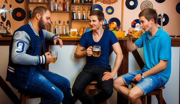 Трое мужчин разговаривают и пьют пиво в баре — стоковое фото
