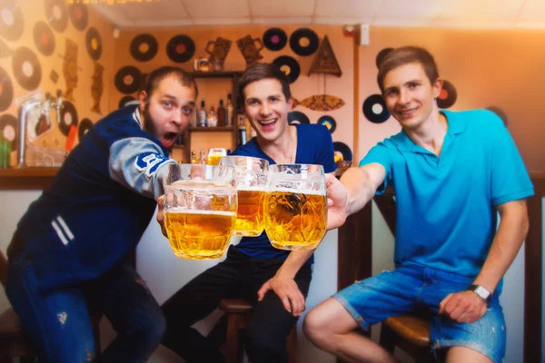 Три веселых человека звонят бокалам пива в баре — стоковое фото