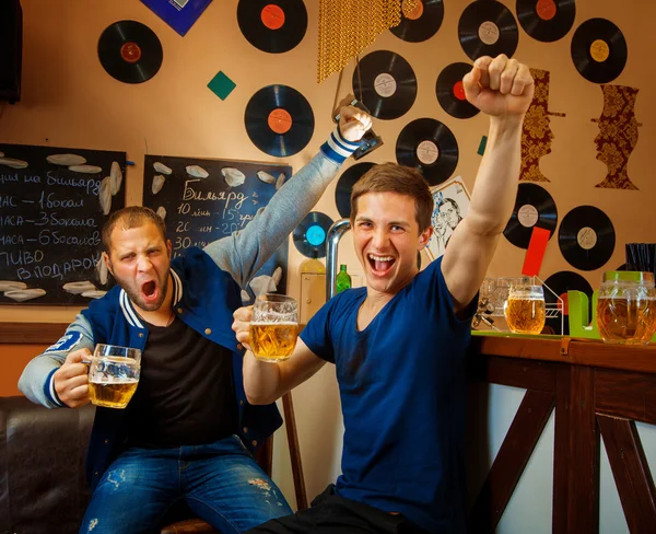 two friends drink beer in bar and have fun