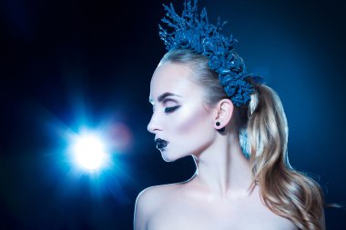 Pretty young girl with wreath on head and nice makeup on black b