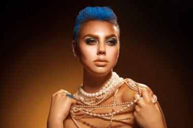 Cute woman with short blue hairstyle and green makeup looking aw