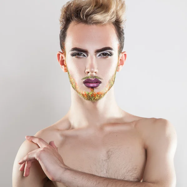 Modelo masculino atraente olhando para a câmera com maquiagem e multicol — Fotografia de Stock