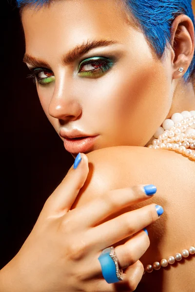 Attractive young woman with blue nails looking at camera