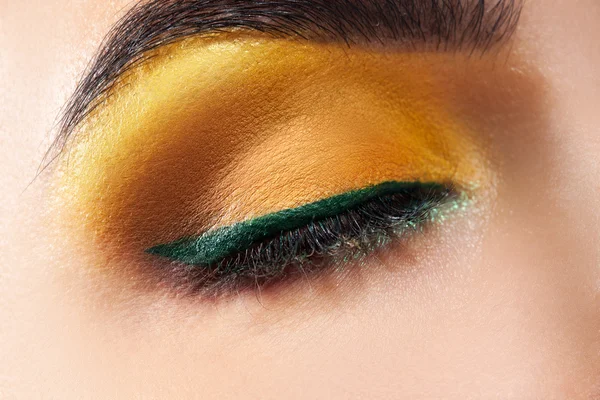 Closed woman eye with yellow makeup and green stripe — Stock Photo, Image