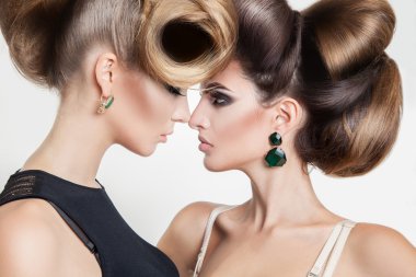 Portrait of two sexy women in studio with volume creative hairst