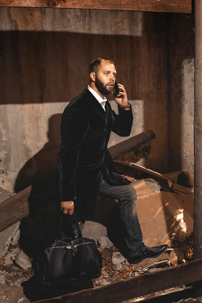 Hombre en traje negro con maletín caminando al aire libre y hablando ph —  Fotos de Stock