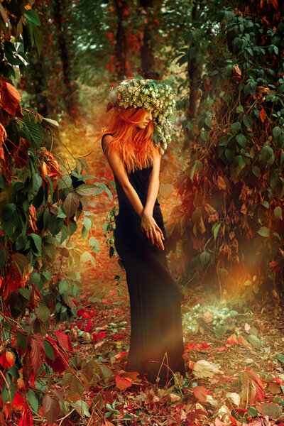 Elegance beauty lady posing in forest with wreath of hop on head outdoors