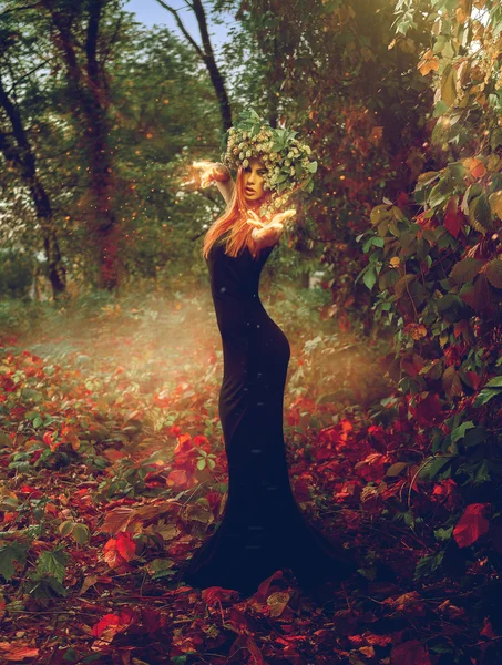 Foto vertical da adorável bruxa ruiva evoca na floresta — Fotografia de Stock