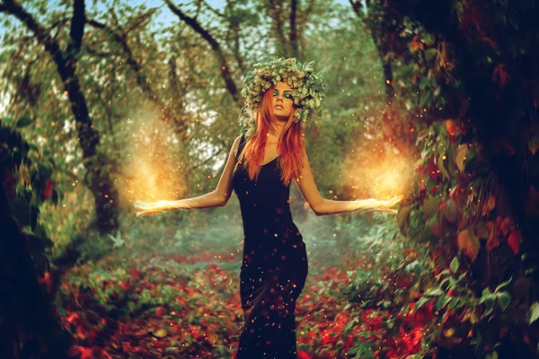 Élégante rousse fille sorcière évoque dans la forêt magique Image En Vente